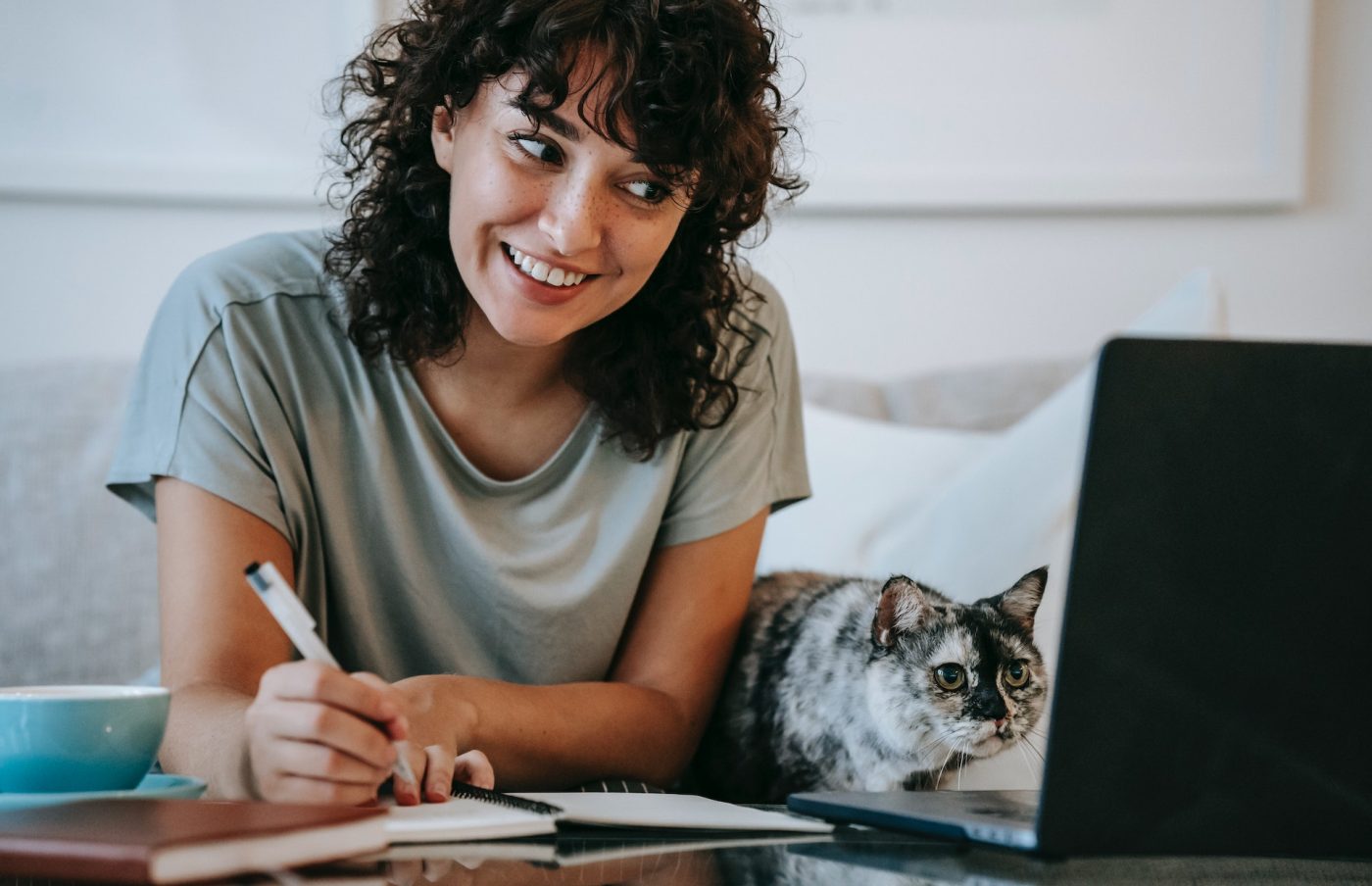 millennial woman sitting at a computer desk with a pencil in her had listening to a virtual consultation with  a Lasik Vision Institute surgeon and her cat is sitting on the desk next to her.