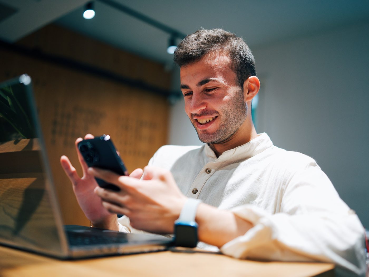millennial male with a white collar shirt, wearing an apple watch and holding his phone while listening to a lasik vision institute surgeon during their virtual consultation