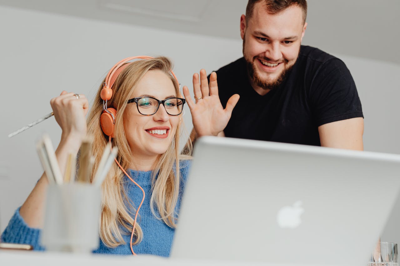 couple waving at the laptop screen during a virtual consultation